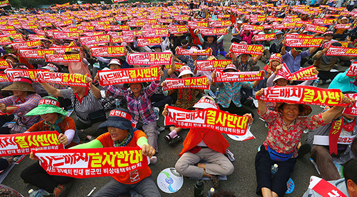 Thousands of South Korean residents hold up red banners reading "We absolutely oppose THAAD deployment