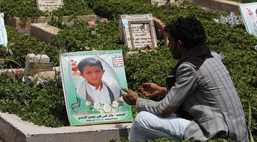 A Yemeni father sitting next to his son's grave 