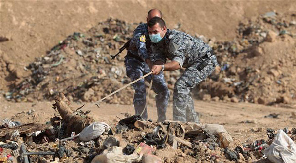 Iraqi soldiers dig up a mass grave
